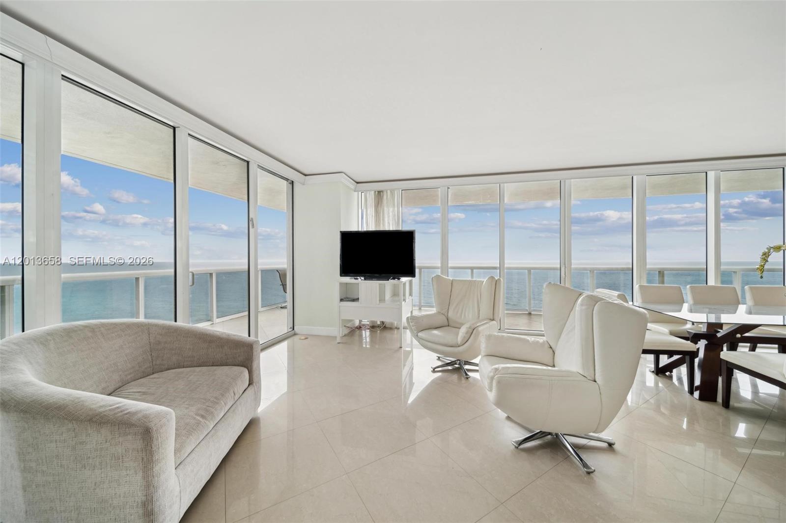 A bright living and dining area features floor-to-ceiling windows with expansive ocean views — 1830 S Ocean Dr # 1701, Hallandale Beach FL 33009, HALLANDALE BEACH, FL
