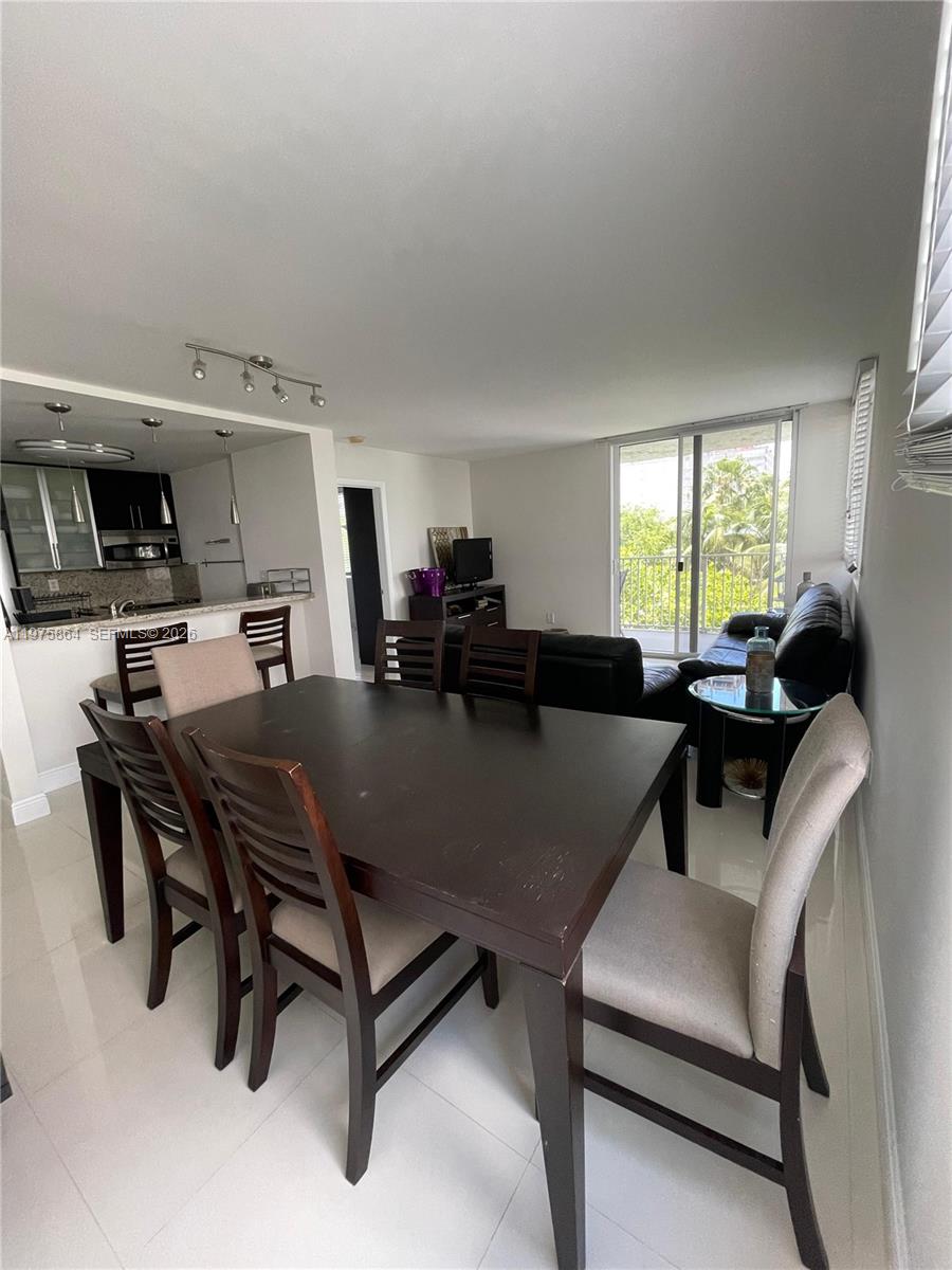A dining area with a dark wood table and chairs sits adjacent to an open kitchen — 800 N Miami Ave # 408, Miami FL 33136, MIAMI, FL