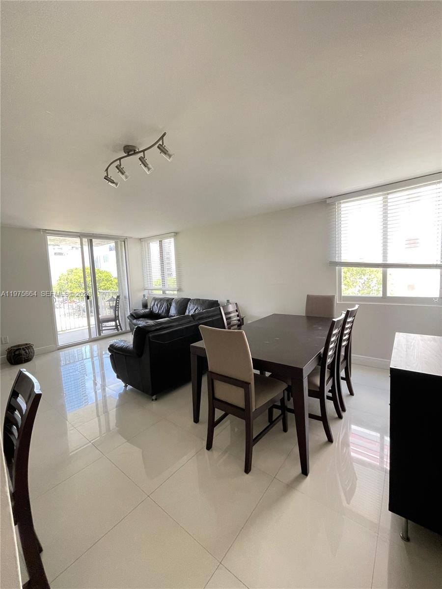 A dining and living area features white tile floors, a dark wood table, and sliding doors — 800 N Miami Ave # 408, Miami FL 33136, MIAMI, FL