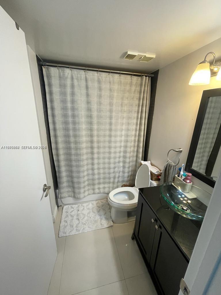 A bathroom features a glass vessel sink, a black vanity, and a shower with curtains — 800 N Miami Ave # 408, Miami FL 33136, MIAMI, FL