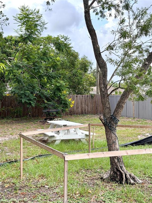 A backyard features a white picnic table, a tree with string lights, and wooden fencing — 2101 ROSE STREET, SARASOTA, FL