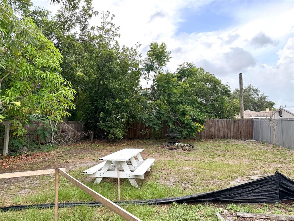 A backyard features a white picnic table on a grassy lawn with trees and fencing — 2101 ROSE STREET, SARASOTA, FL