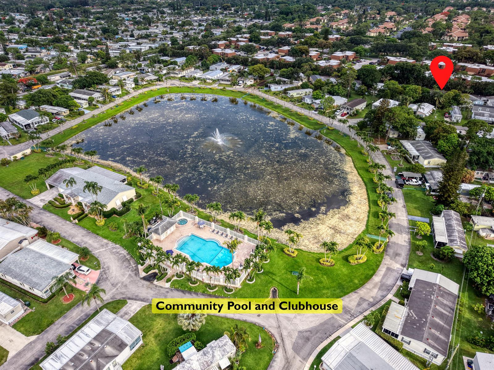 An aerial view shows a community pool, clubhouse, and a large pond with a fountain — 32 Lisa Lane, FL 33463, FL