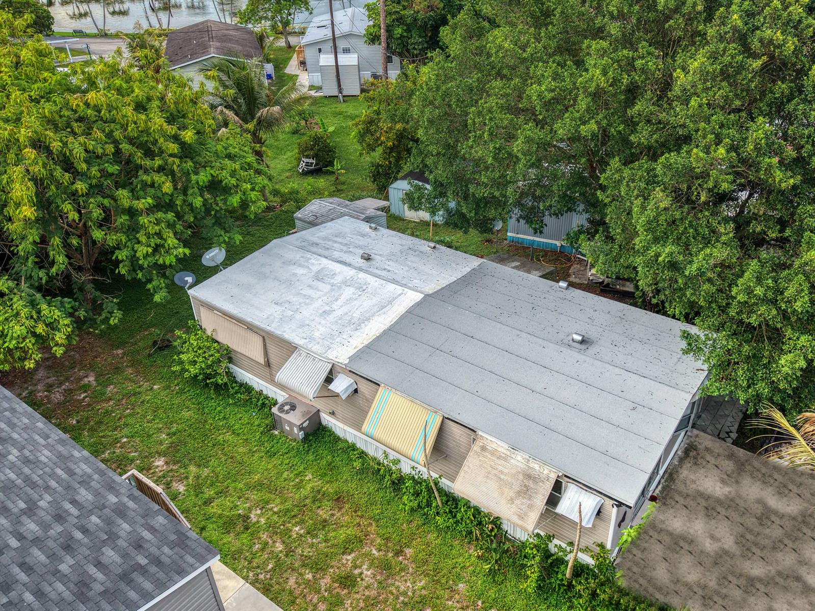An aerial view of a mobile home with a two-toned roof and metal window awnings — 32 Lisa Lane, FL 33463, FL