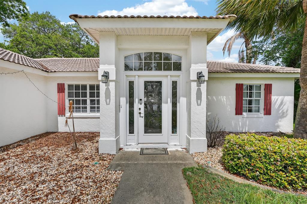 The exterior of a white house features a covered entryway with a decorative glass door — 1 WELLWATER DRIVE, PALM COAST, FL