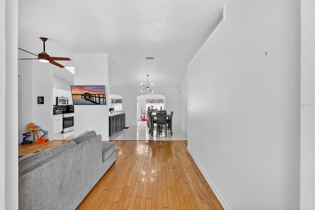 A living room with hardwood floors leads to a kitchen and dining area with tile — 1 WELLWATER DRIVE, PALM COAST, FL