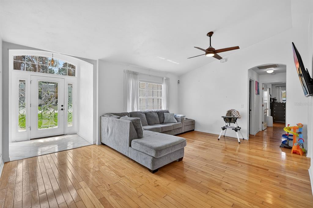 A living room features hardwood floors, a gray sectional sofa, and a glass-paneled front door — 1 WELLWATER DRIVE, PALM COAST, FL