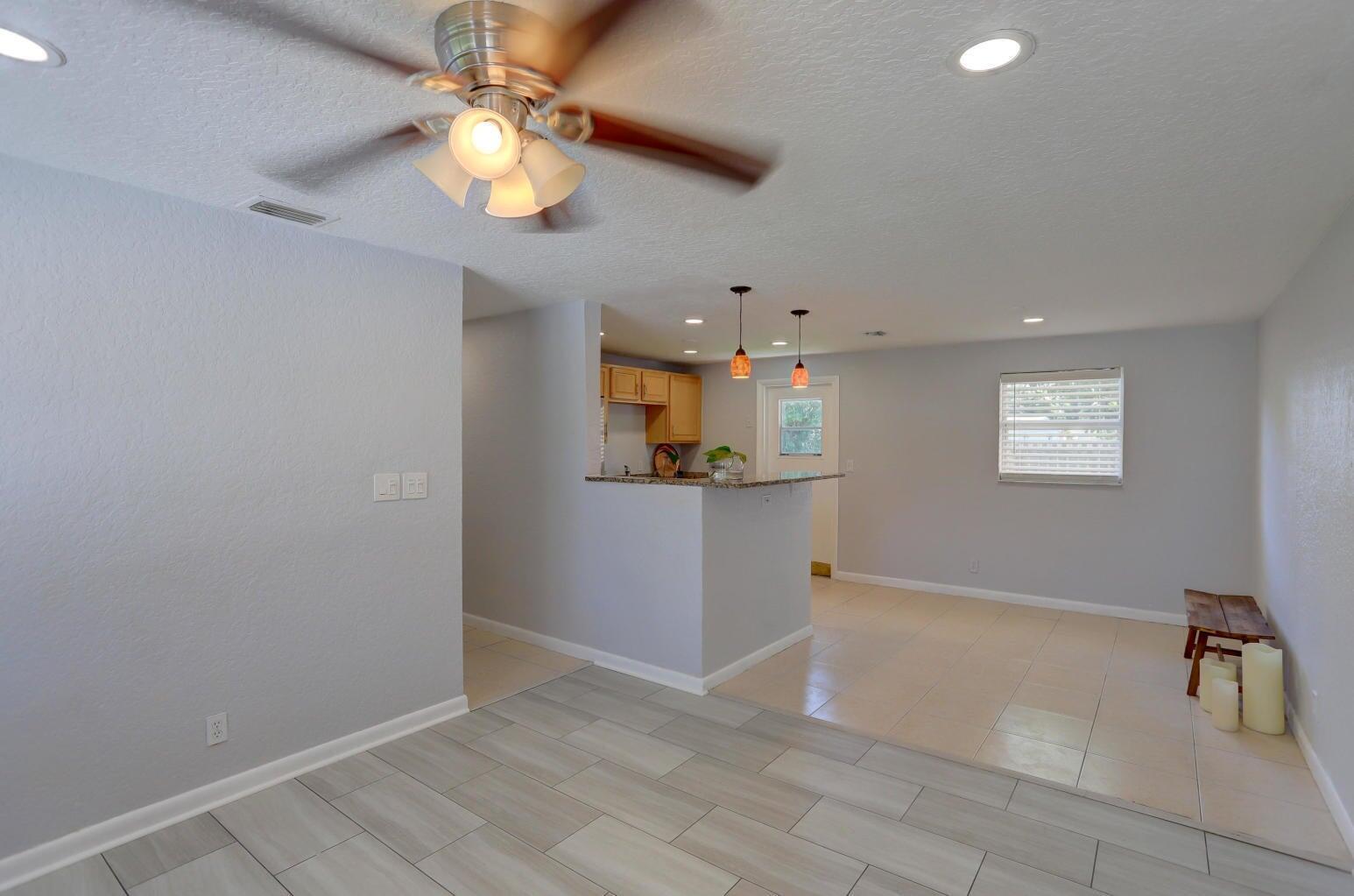 An open-concept living area features light gray walls, tile flooring, and a kitchen breakfast bar — 314 NW 12th Avenue, Delray Beach FL 33444, DELRAY BEACH, FL