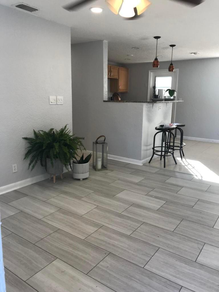 A living room with light gray walls, wood-look tile flooring, and a kitchen breakfast bar — 314 NW 12th Avenue, Delray Beach FL 33444, DELRAY BEACH, FL