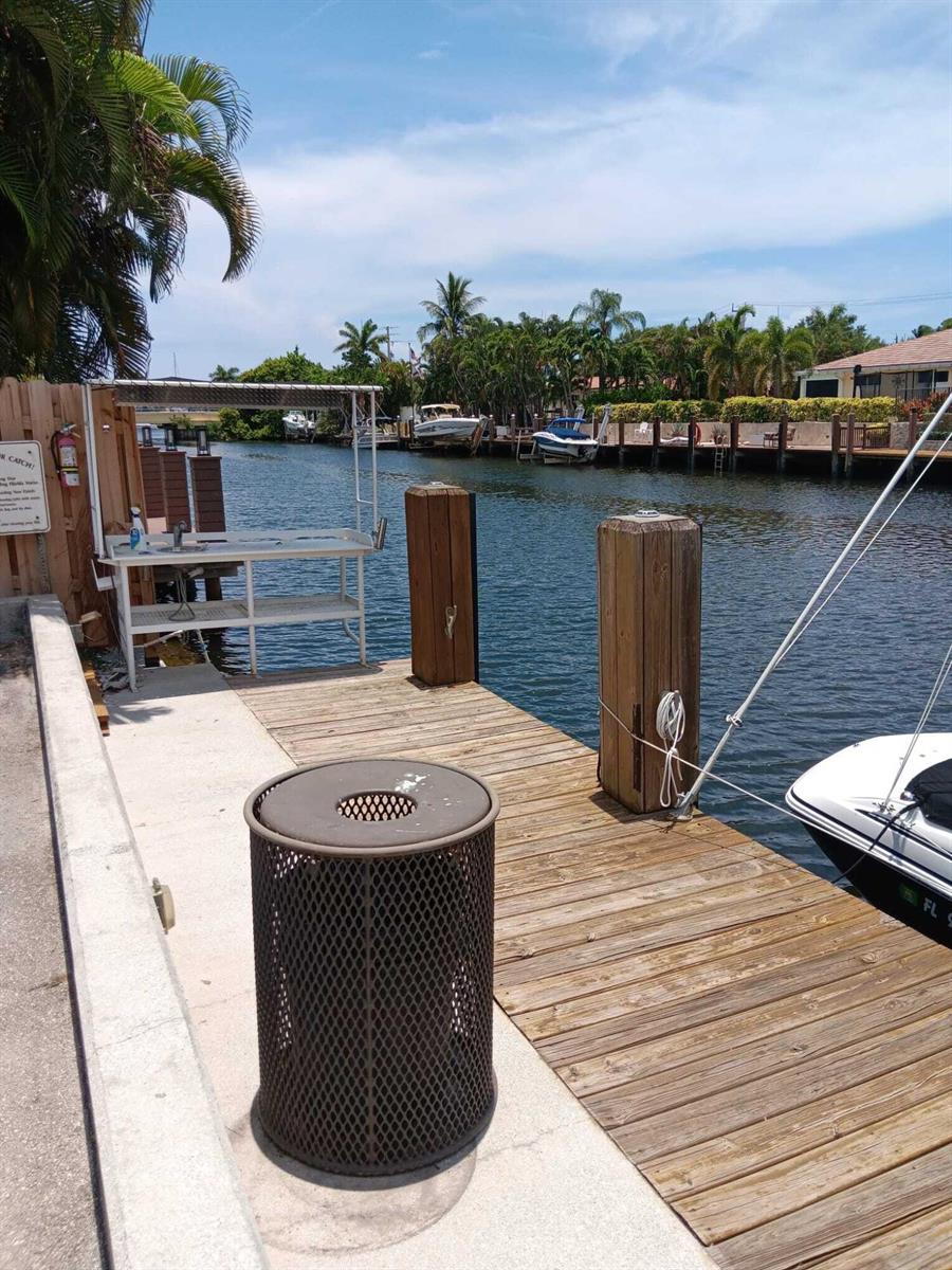 A wooden boat dock features a fish cleaning station, a trash receptacle, and moored boats — 4502 N Federal Highway # D, Lighthouse Point FL 33064, LIGHTHOUSE POINT, FL