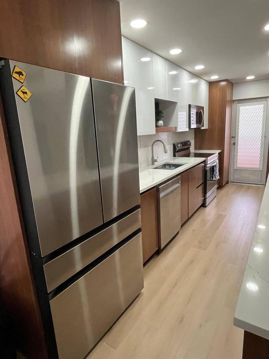 A galley kitchen features stainless steel appliances, white upper cabinets, wood lower cabinets, and light flooring — 4502 N Federal Highway # D, Lighthouse Point FL 33064, LIGHTHOUSE POINT, FL