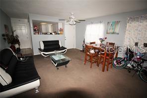 A living room with brown carpet, two black and white sofas, and a dining set — 1000 S SEMORAN BOULEVARD UNIT 404, WINTER PARK, FL