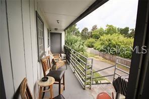 A balcony with wooden chairs, a small table, and a metal railing overlooking greenery — 1000 S SEMORAN BOULEVARD UNIT 404, WINTER PARK, FL