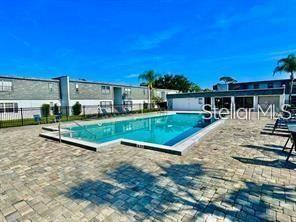 A rectangular swimming pool sits in a paved courtyard surrounded by multi-story apartment buildings — 1000 S SEMORAN BOULEVARD UNIT 404, WINTER PARK, FL