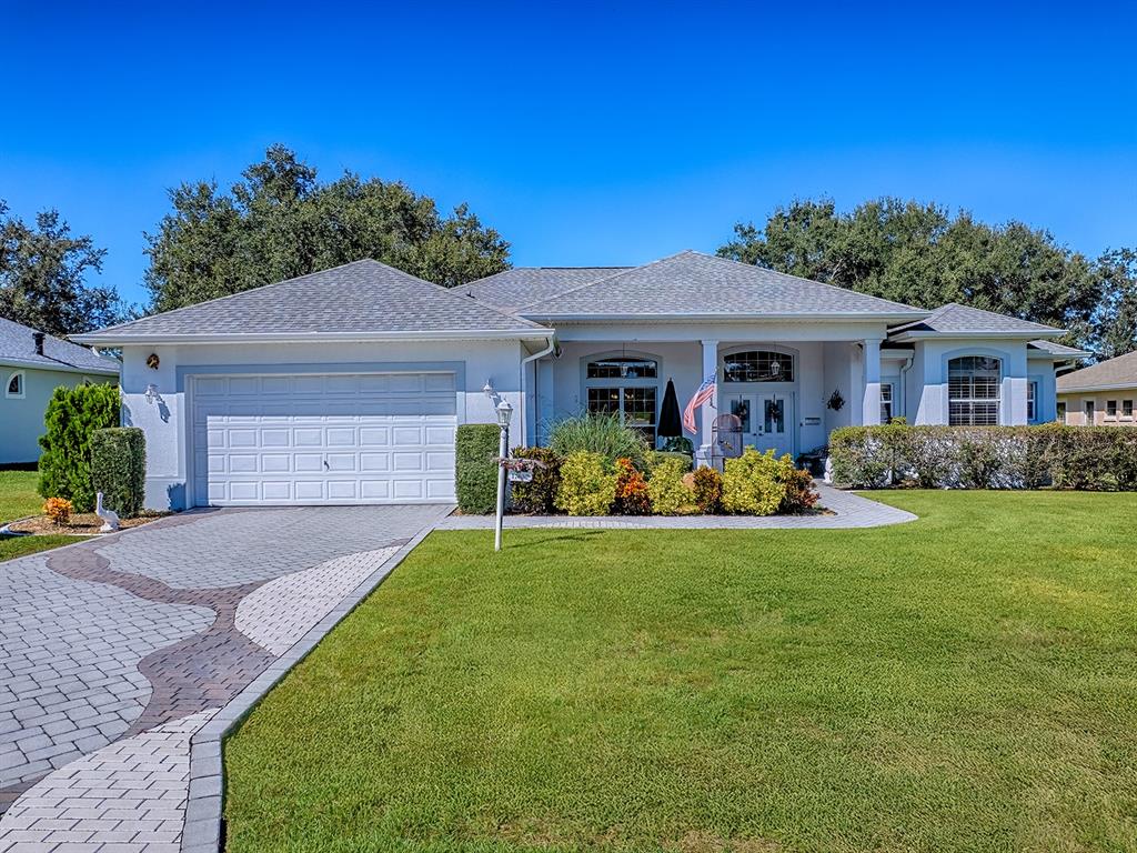 A single-story house with a white exterior, a two-car garage, and a paved driveway — 17627 SE 88TH COVINGTON CIRCLE, THE VILLAGES, FL