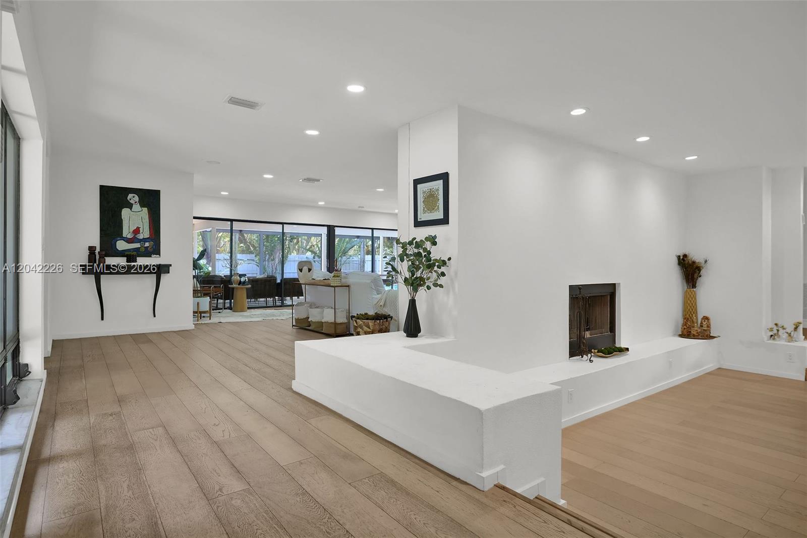 A spacious living area features light wood floors, a white fireplace, and large glass doors — 5801 SW 37th Ter, Dania Beach FL 33312, DANIA BEACH, FL
