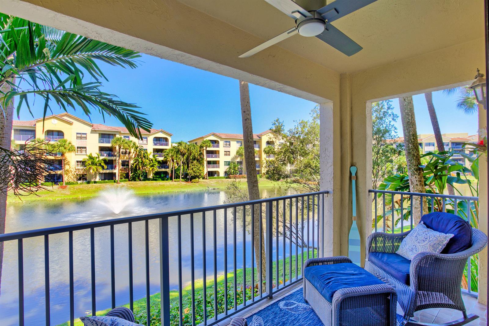 A covered balcony overlooks a pond with a fountain and surrounding apartment buildings — 400 Uno Lago Drive # 204, Juno Beach FL 33408, JUNO BEACH, FL
