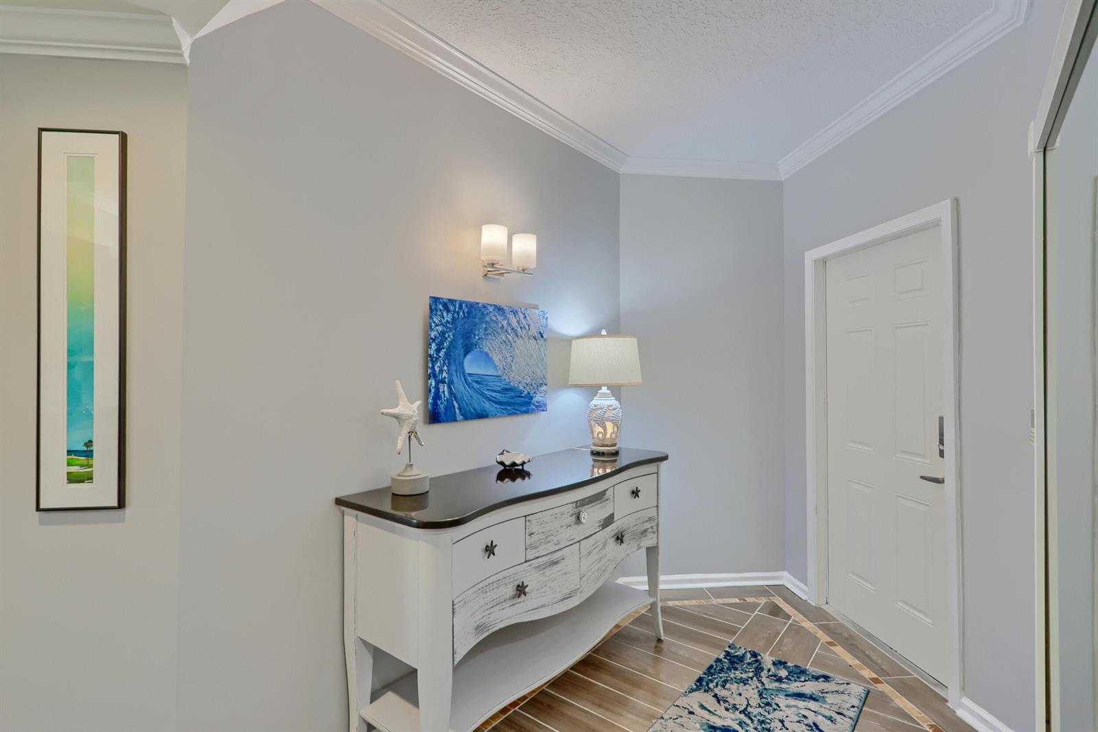 A white console table sits against a gray wall in a coastal-themed entryway — 400 Uno Lago Drive # 204, Juno Beach FL 33408, JUNO BEACH, FL