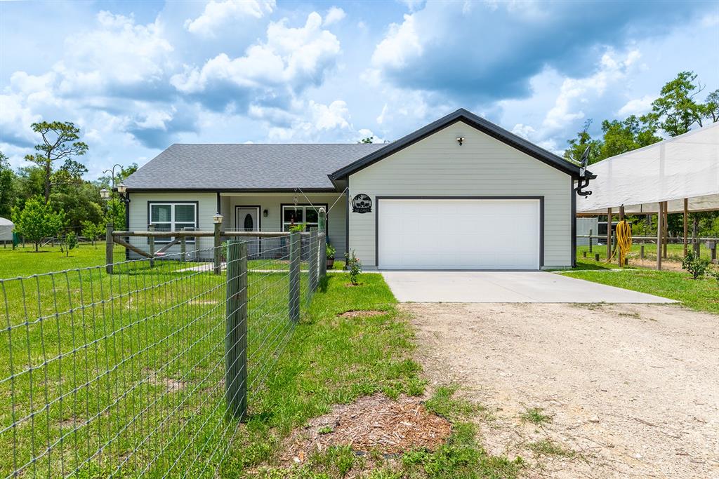 A single-story house with light green siding, a white garage door, and a wire fence — 11030 NW 100TH AVENUE, CHIEFLAND, FL