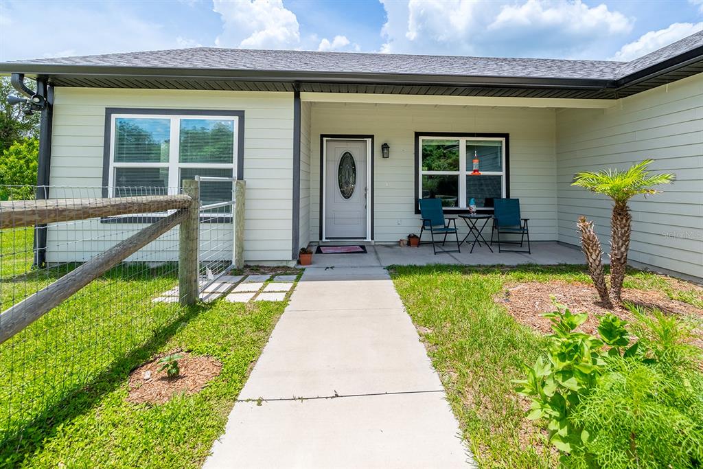 A light-colored house exterior features a front porch, a concrete walkway, and a wire fence — 11030 NW 100TH AVENUE, CHIEFLAND, FL