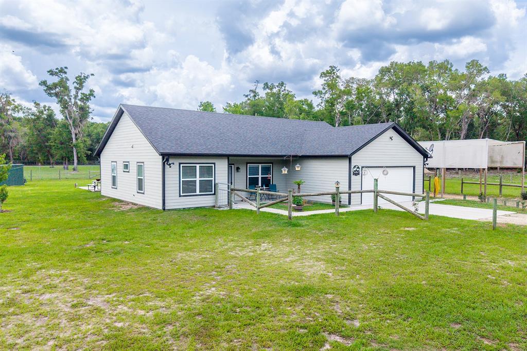 A single-story house with light siding, a dark roof, and an attached garage — 11030 NW 100TH AVENUE, CHIEFLAND, FL