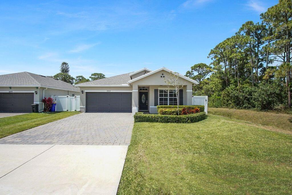 A single-story suburban house with a gray garage, paved driveway, and manicured landscaping — 3909 SE Lee Street, Stuart FL 34997, STUART, FL
