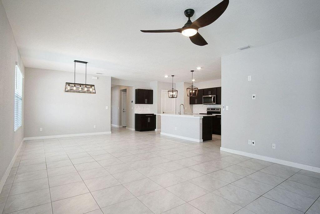 An open-concept kitchen and dining area features tile flooring, dark cabinetry, and pendant lighting — 3909 SE Lee Street, Stuart FL 34997, STUART, FL