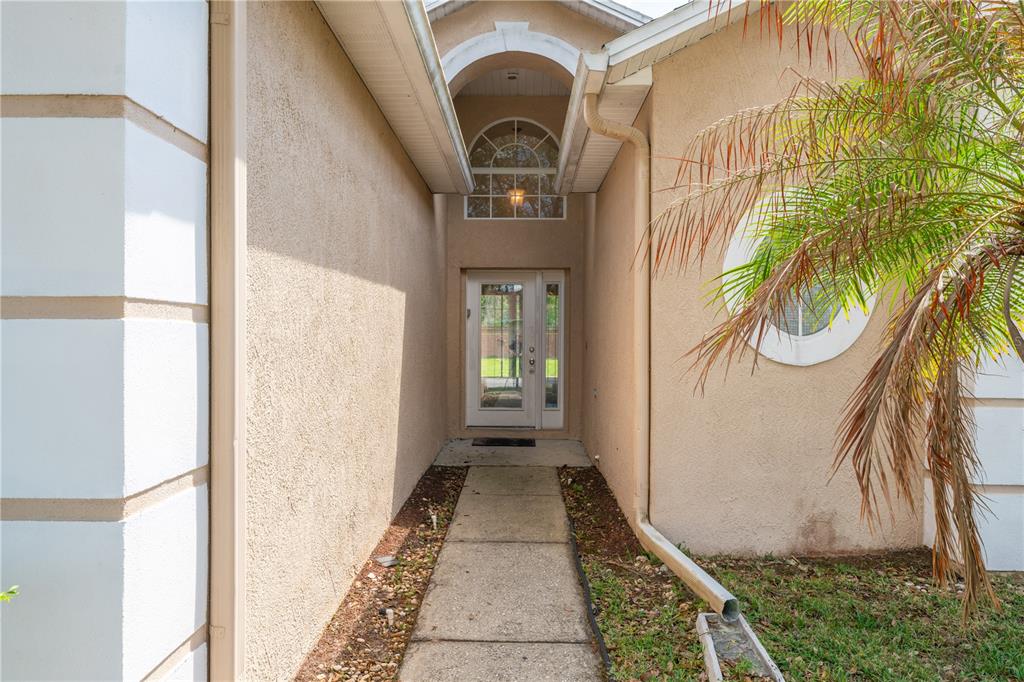A concrete walkway leads to the front entrance of a house with a glass door — 2563 ASTER COVE LANE, KISSIMMEE, FL