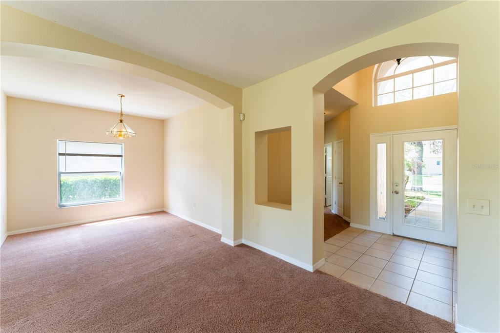 A carpeted dining area opens to a tiled entryway with an arched doorway and window — 2563 ASTER COVE LANE, KISSIMMEE, FL