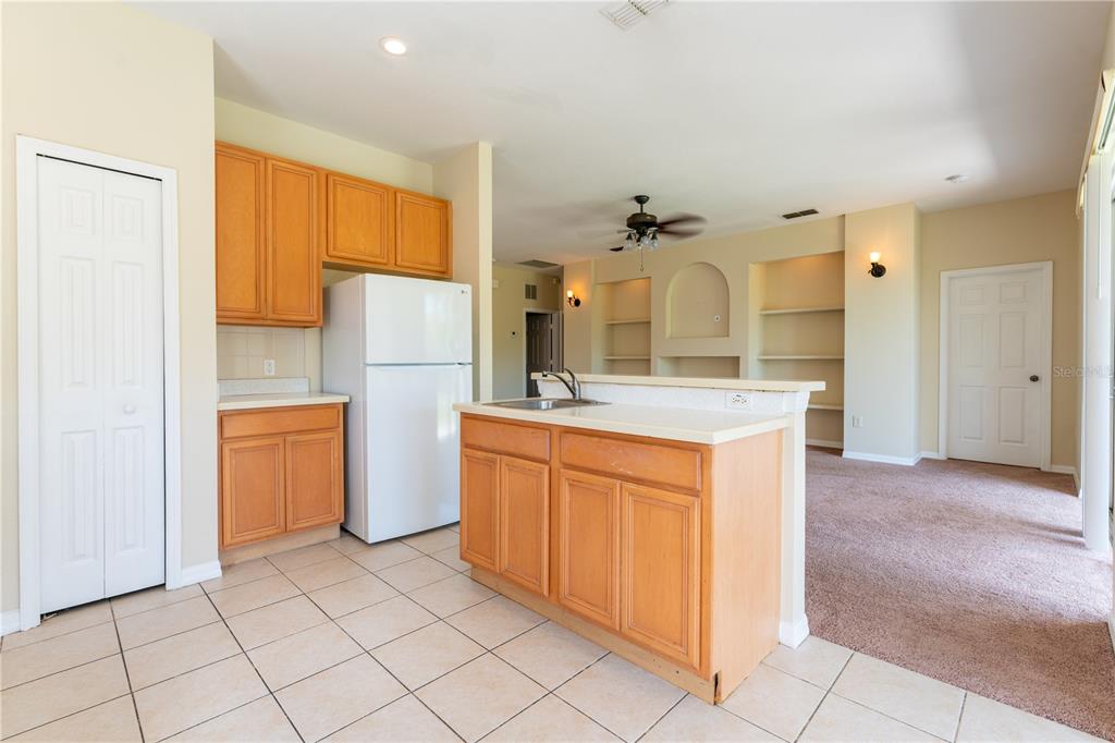 A kitchen with light wood cabinets, a white refrigerator, and a tiled floor — 2563 ASTER COVE LANE, KISSIMMEE, FL