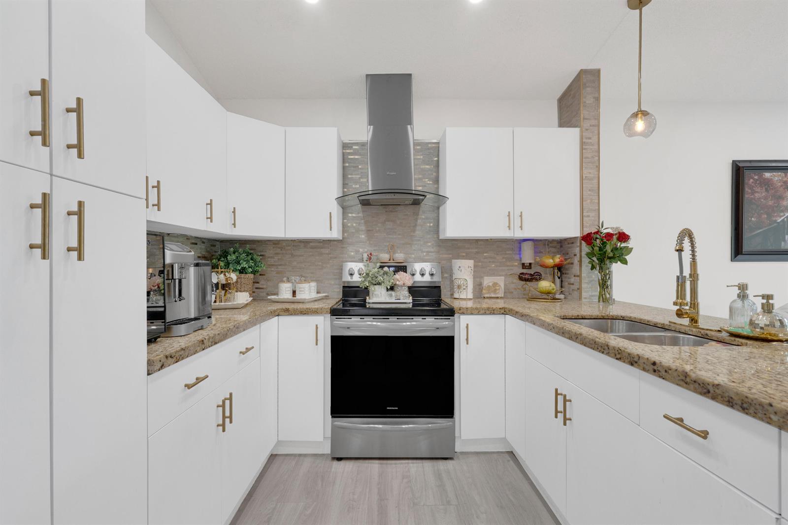 A kitchen features white cabinets, gold hardware, granite countertops, and stainless steel appliances — 17901 SW 144th Avenue, Miami FL 33177, MIAMI, FL