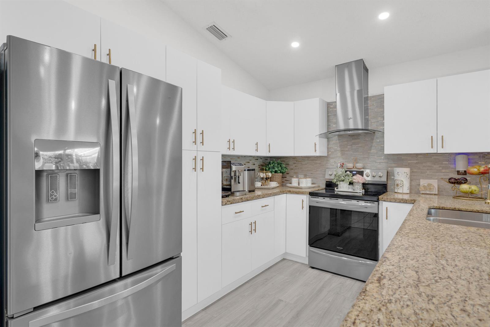 A modern kitchen features white cabinets, stainless steel appliances, and speckled granite countertops — 17901 SW 144th Avenue, Miami FL 33177, MIAMI, FL