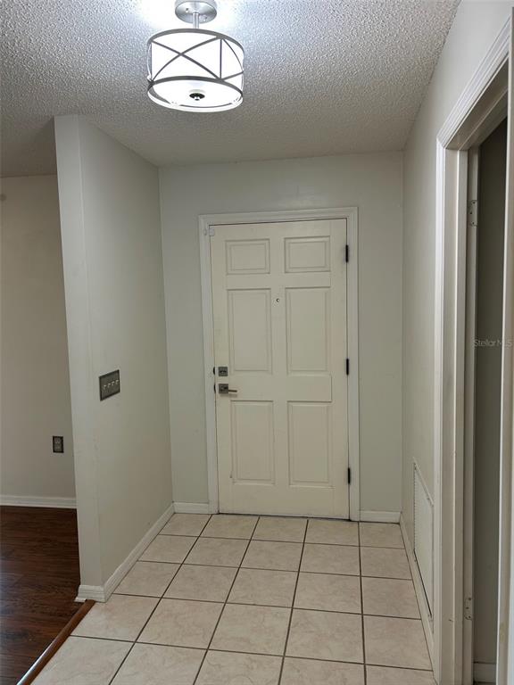 An entryway with a tiled floor, a white front door, and a modern ceiling light — 1605 BLACKBERRY COURT, EUSTIS, FL