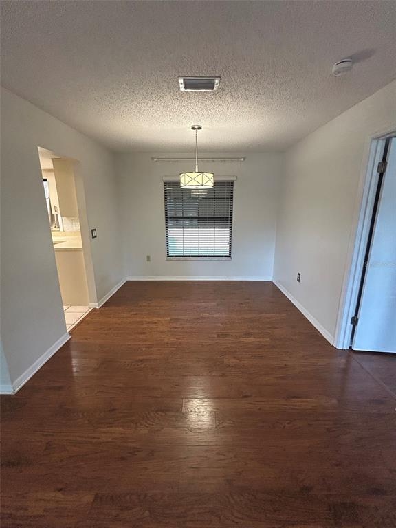 A dining room features wood-look flooring, a central pendant light, and a window with blinds — 1605 BLACKBERRY COURT, EUSTIS, FL