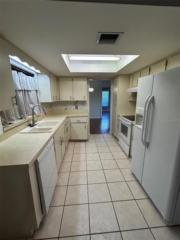 A kitchen with white appliances, light-colored cabinets, tile flooring, and a recessed ceiling light — 1605 BLACKBERRY COURT, EUSTIS, FL