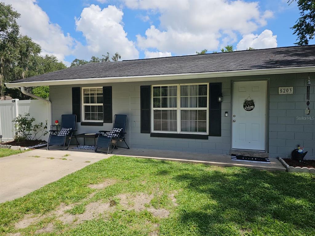 A gray single-story house with black shutters, a white front door, and two patio chairs — 5203 SE 114TH STREET, BELLEVIEW, FL