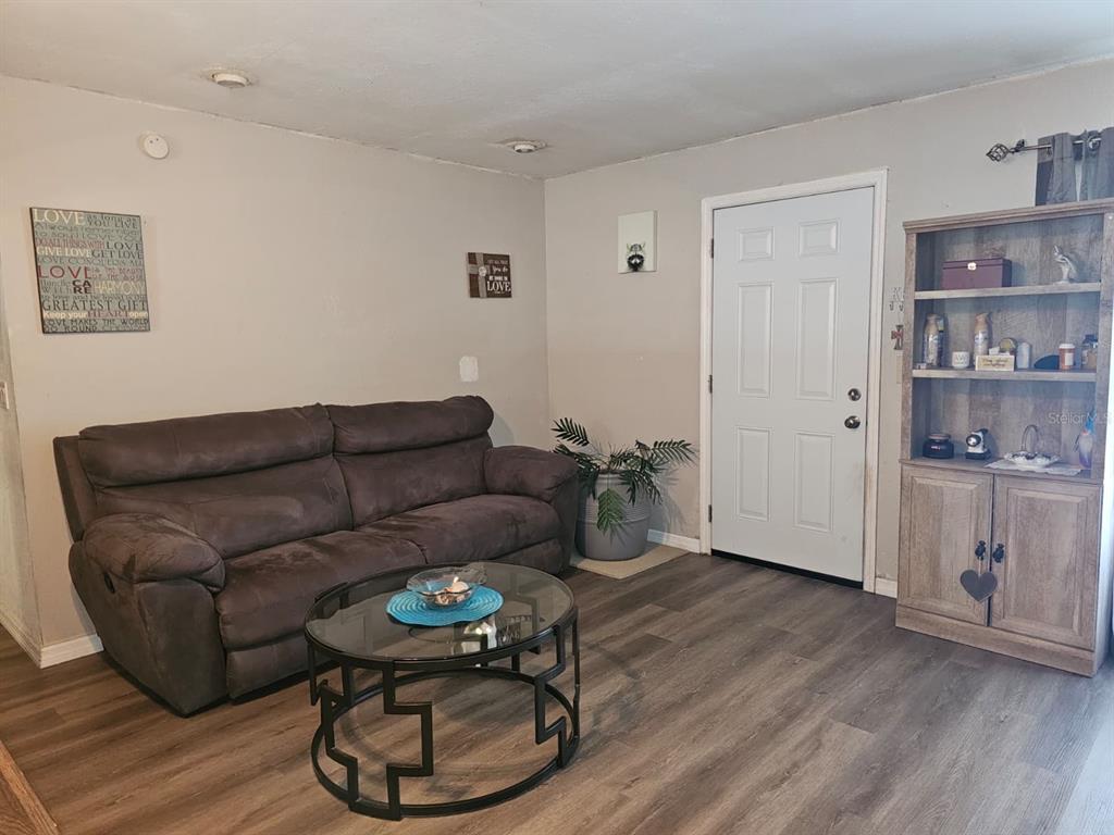 A living room features a brown sofa, a glass coffee table, and a wooden bookshelf — 5203 SE 114TH STREET, BELLEVIEW, FL