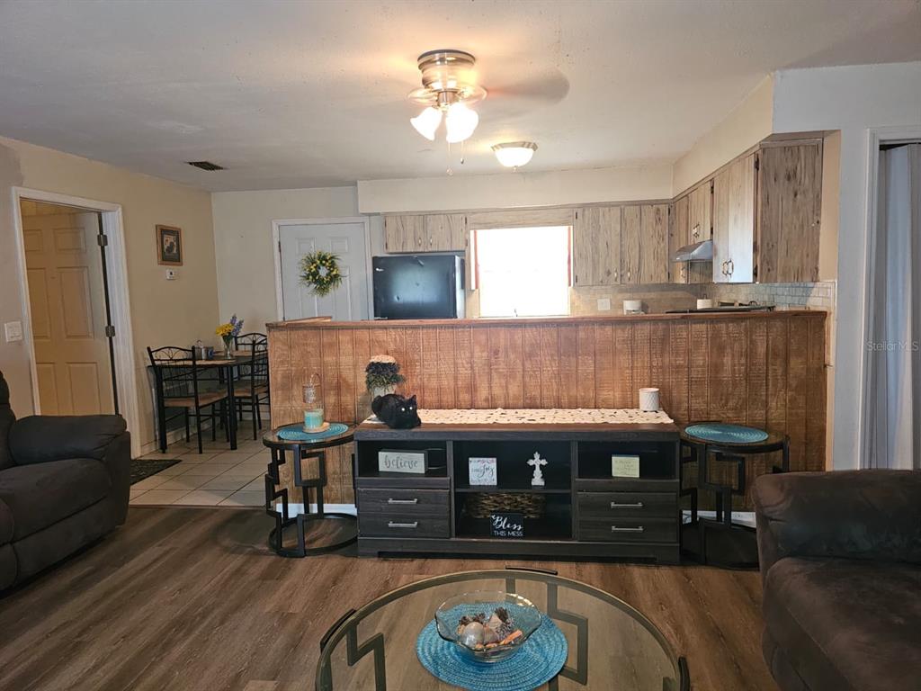 A living room with wood-look flooring features a wooden half-wall separating it from the kitchen — 5203 SE 114TH STREET, BELLEVIEW, FL