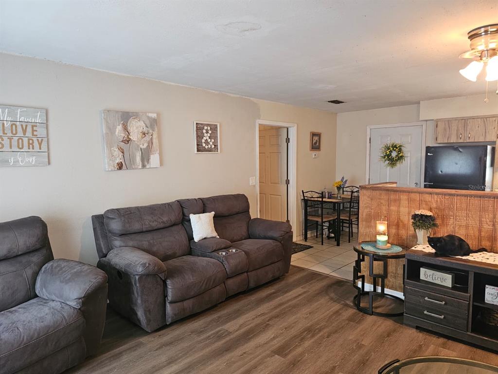 A living room features wood-look flooring, a gray sofa, and a partial wood-paneled wall — 5203 SE 114TH STREET, BELLEVIEW, FL