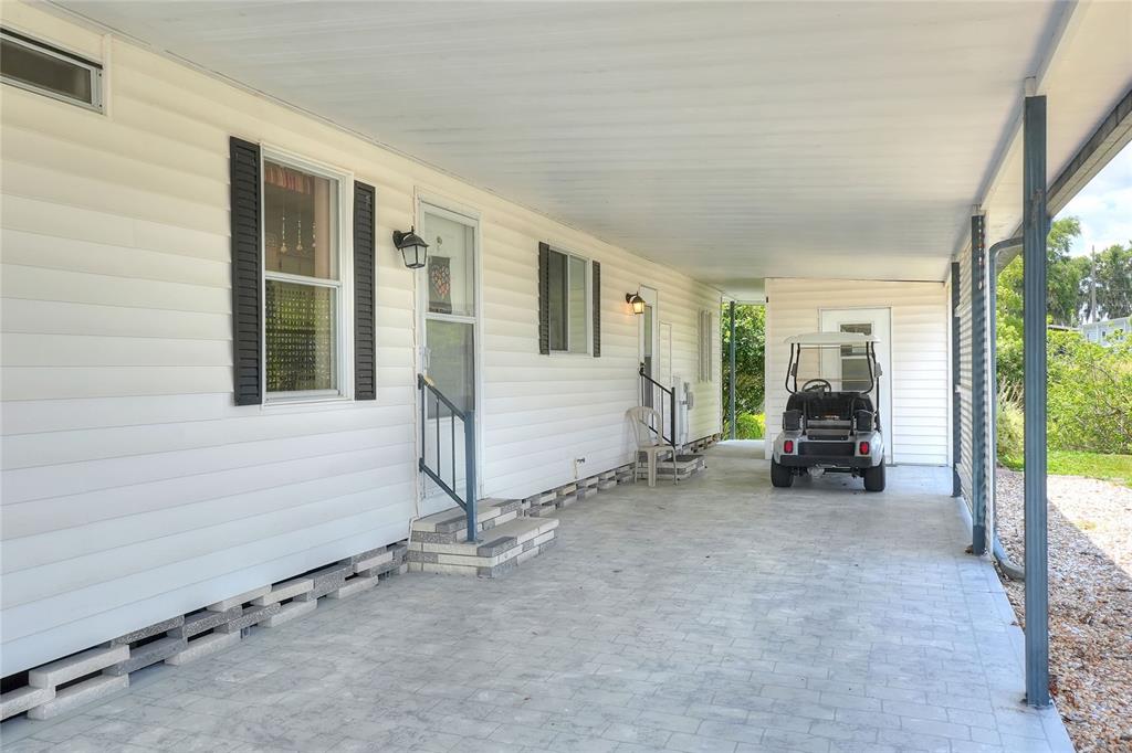 A covered carport with a concrete floor leads to the side entrance of a home — 2055 S FLORAL AVENUE UNIT 246, BARTOW, FL