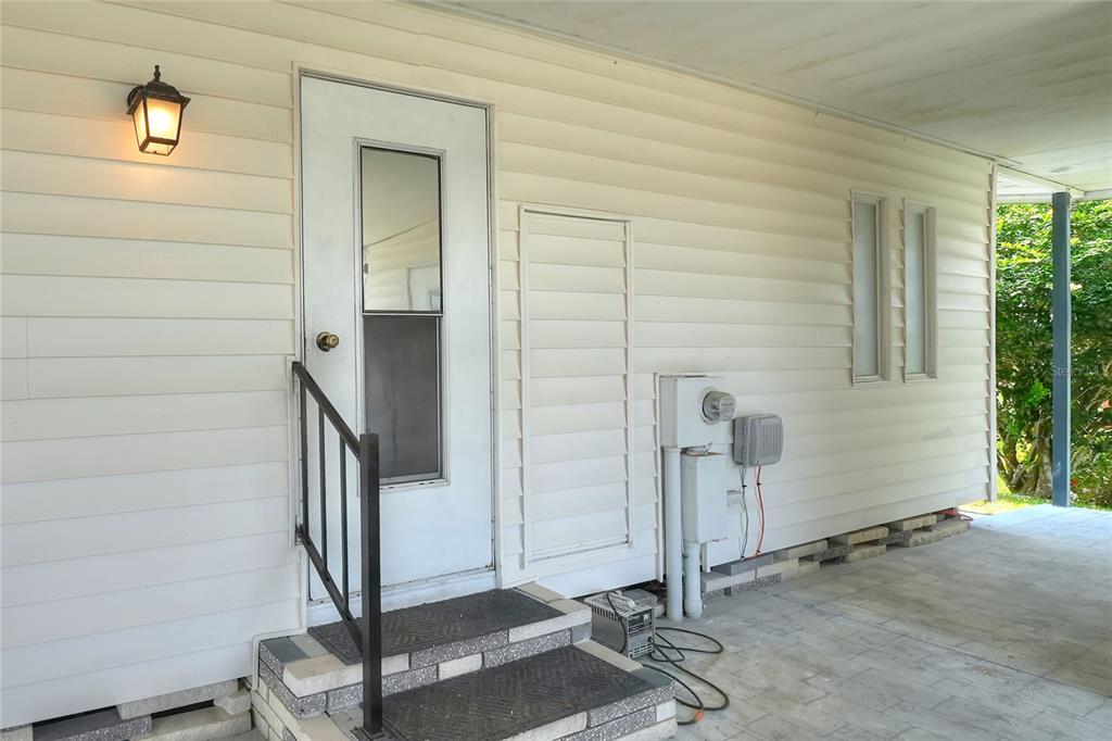 A white-sided exterior wall features a front door, steps, and an electrical meter — 2055 S FLORAL AVENUE UNIT 246, BARTOW, FL