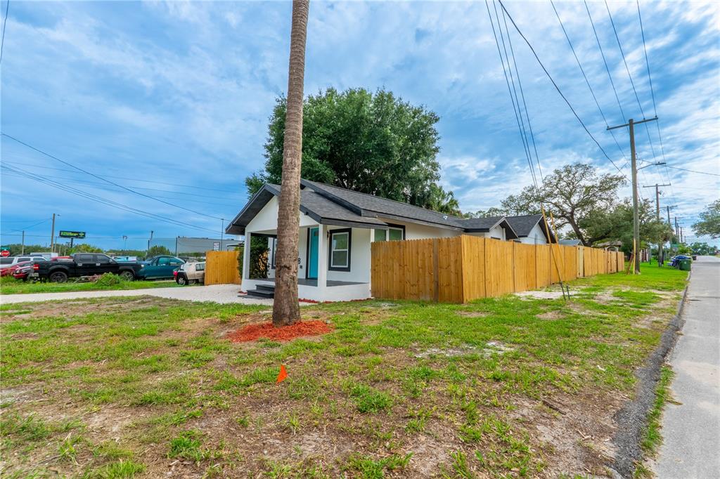 A single-story house with a white exterior and a wooden fence sits on a lot — 8408 N SEMINOLE AVENUE, TAMPA, FL