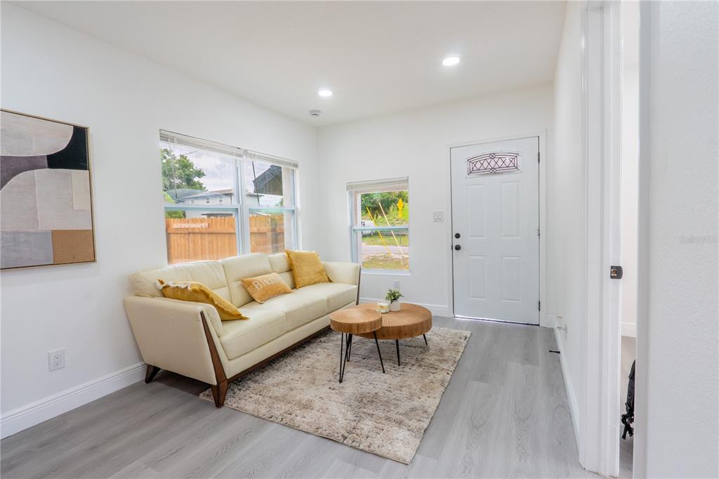 A living room features a white sofa, a rug, two round coffee tables, and a door — 8408 N SEMINOLE AVENUE, TAMPA, FL