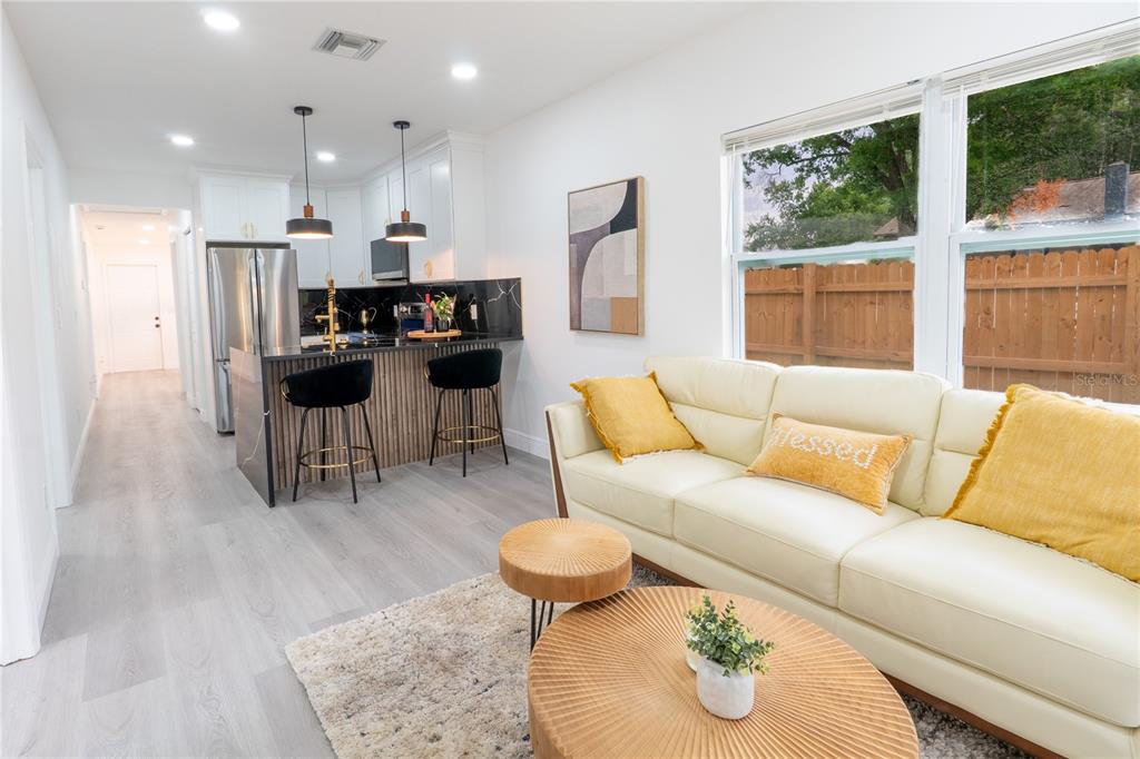 A modern open-concept kitchen and living area features a breakfast bar, white cabinetry, and sofa — 8408 N SEMINOLE AVENUE, TAMPA, FL