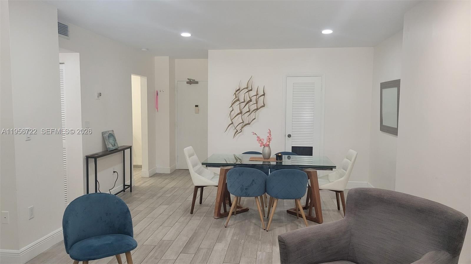 A dining area features a glass-top table, blue chairs, and light wood-look flooring — 1965 S Ocean Dr, Hallandale Beach FL 33009, HALLANDALE BEACH, FL