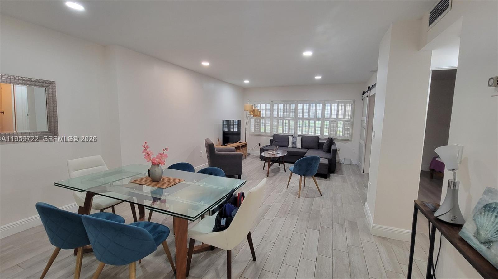 An open-concept living and dining area features light wood-look tile flooring and white walls — 1965 S Ocean Dr, Hallandale Beach FL 33009, HALLANDALE BEACH, FL