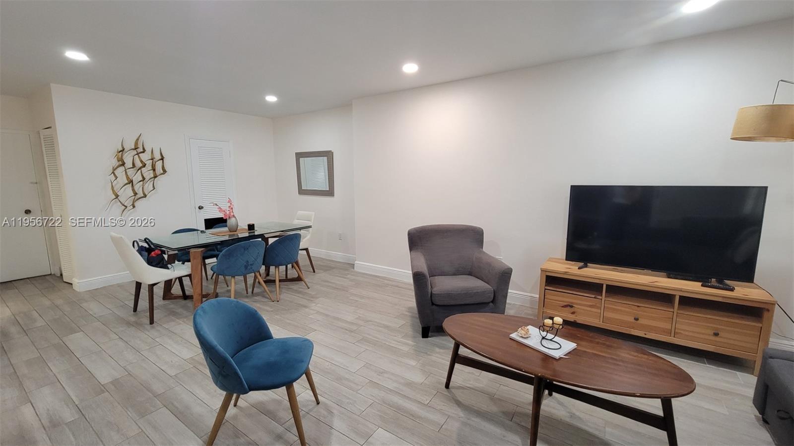 A living and dining area features light wood-look tile floors, a television, and blue chairs — 1965 S Ocean Dr, Hallandale Beach FL 33009, HALLANDALE BEACH, FL