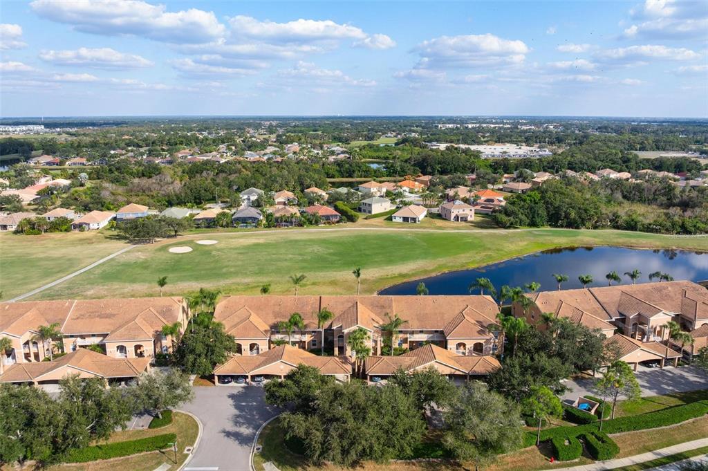 An aerial view shows a multi-unit residential building overlooking a golf course and pond — 915 FAIRWAYCOVE LANE UNIT 204, BRADENTON, FL