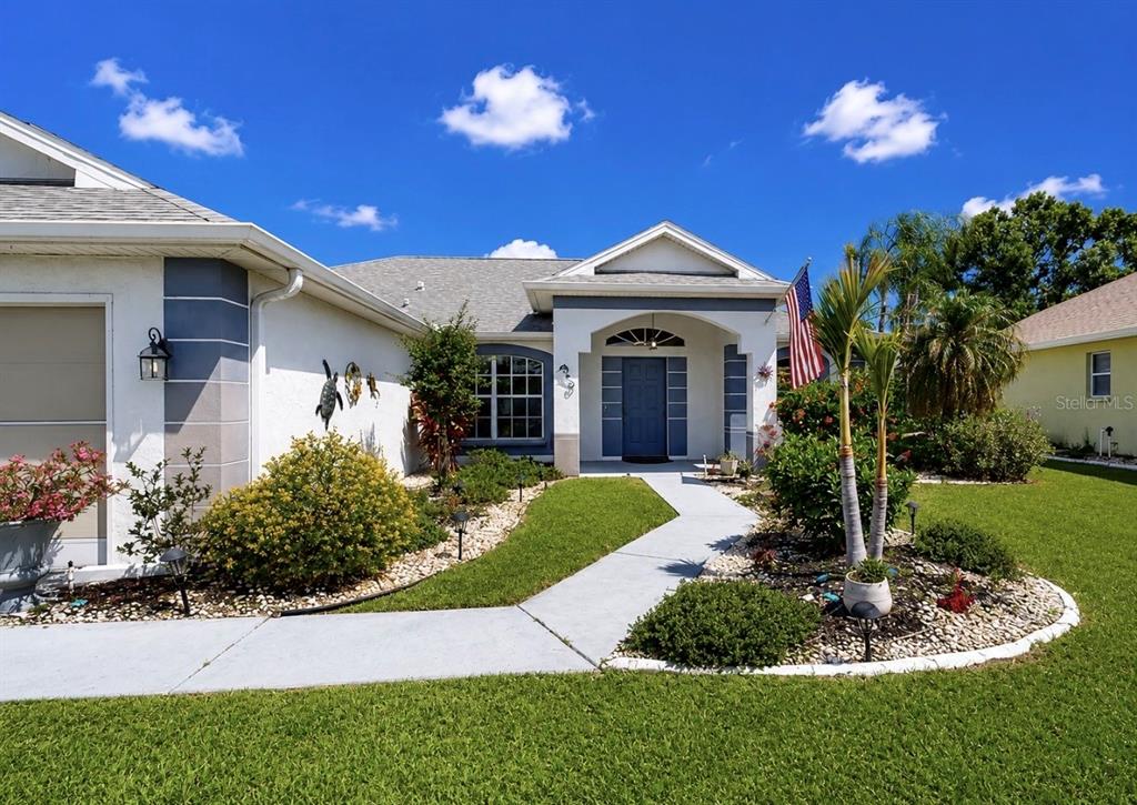 A single-story house with a white exterior, blue front door, and a landscaped front yard — 2240 W DEL WEBB BOULEVARD UNIT 163, SUN CITY CENTER, FL