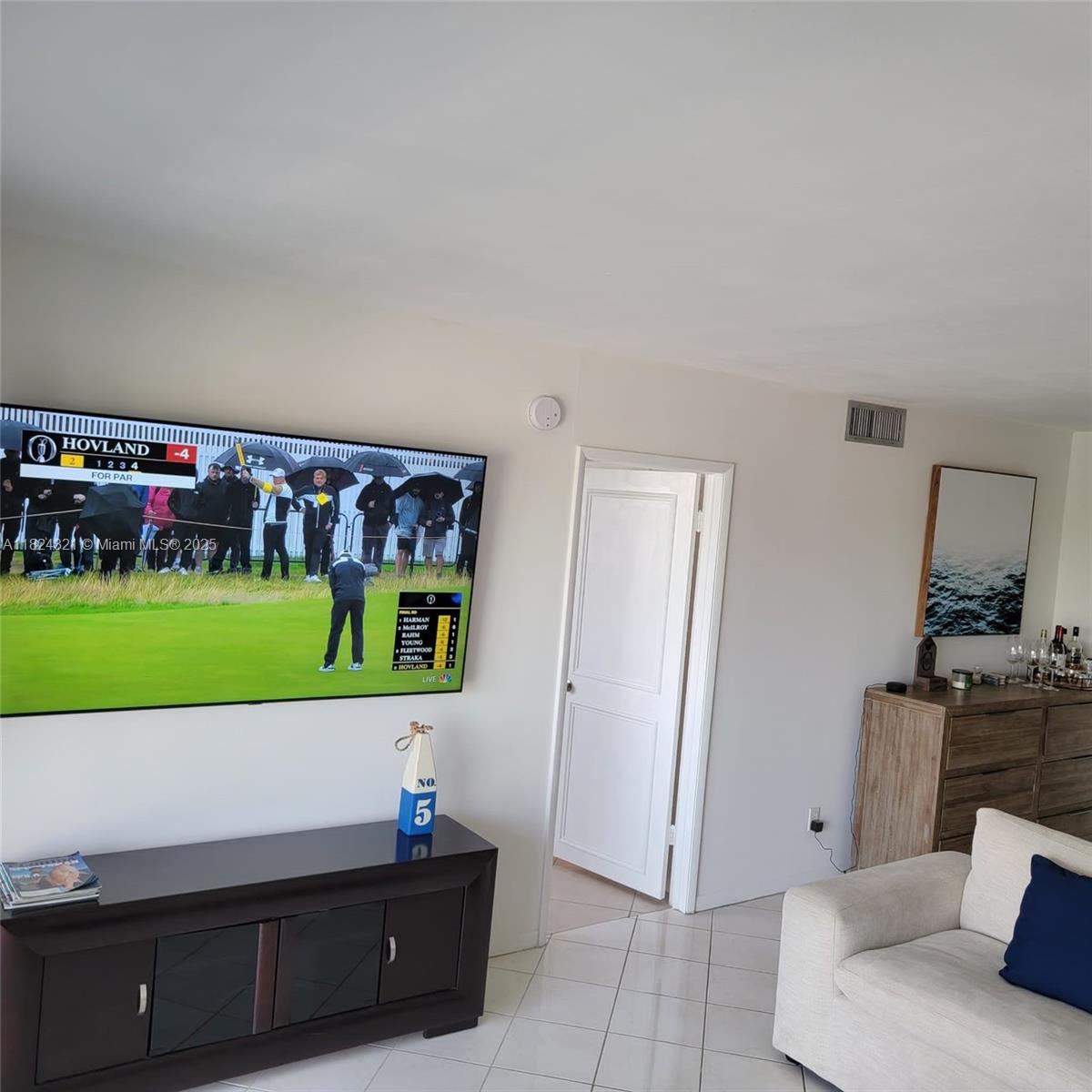 A living room features a wall-mounted television, a dark wood media console, and tile flooring — 2731 NE 14th St Cswy # 636, Pompano Beach FL 33062, POMPANO BEACH, FL